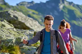 Junger Mann auf einer YOUNG LINE TRAVEL Gruppenreise für junge Leute wandert konzentriert auf einem felsigen Pfad in den Albanischen Alpen.