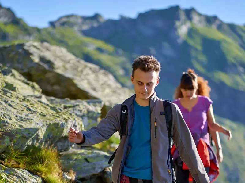 Junger Mann auf einer YOUNG LINE TRAVEL Gruppenreise für junge Leute wandert konzentriert auf einem felsigen Pfad in den Albanischen Alpen.