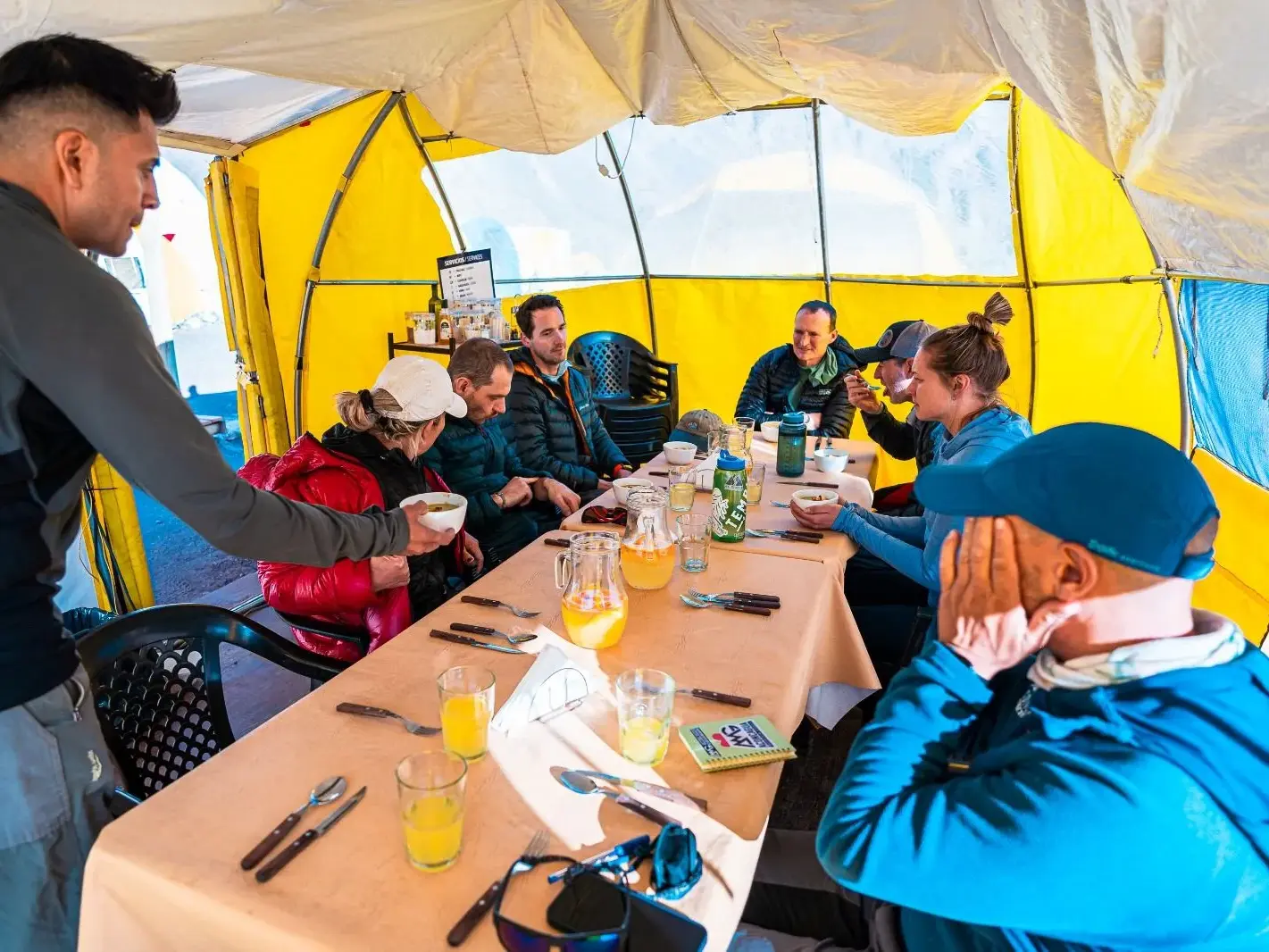 Eine Trekking-Gruppe bei einer gemeinsamen Mahlzeit im gelben Gemeinschaftszelt im Basislager Plaza de Mulas am Aconcagua.