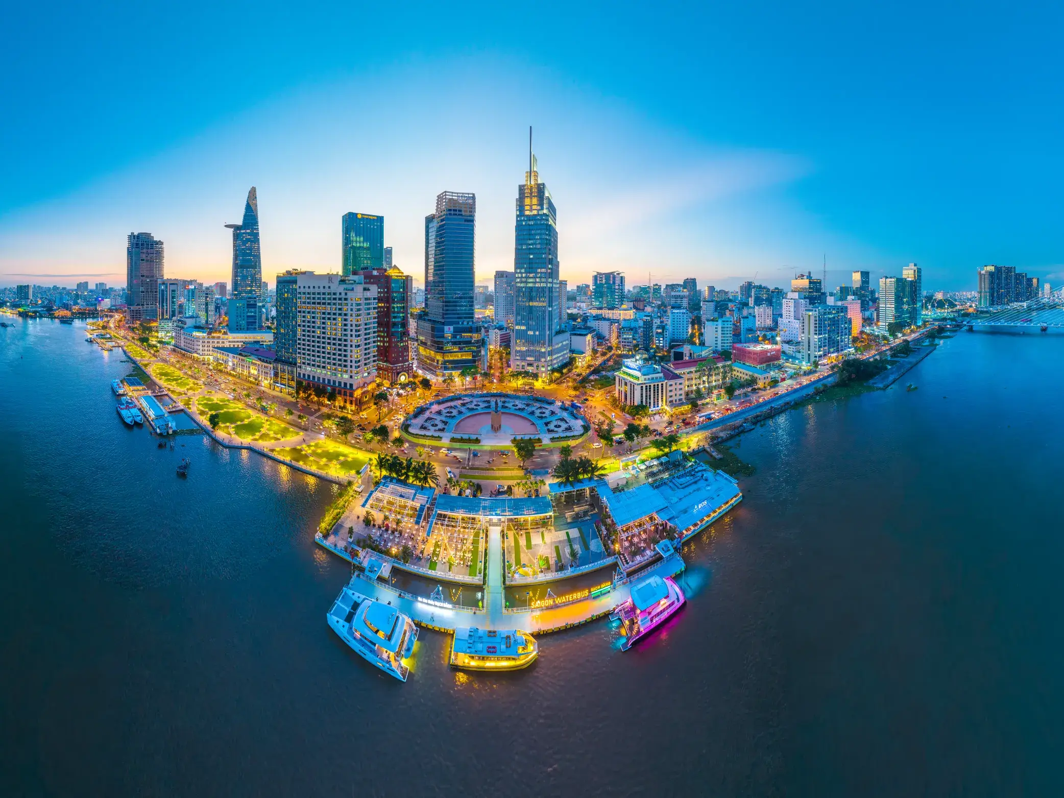 Panoramablick auf die leuchtende Skyline von Ho-Chi-Minh-Stadt bei Nacht mit modernen Wolkenkratzern am Ufer des Saigon-Flusses.