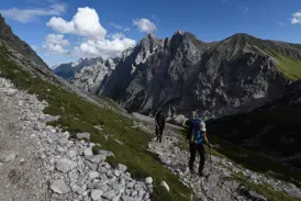 Zwei Wanderer mit Trekkingrucksäcken auf einem steinigen Bergpfad im Reintal während der Hauser-Tour zur Zugspitze.