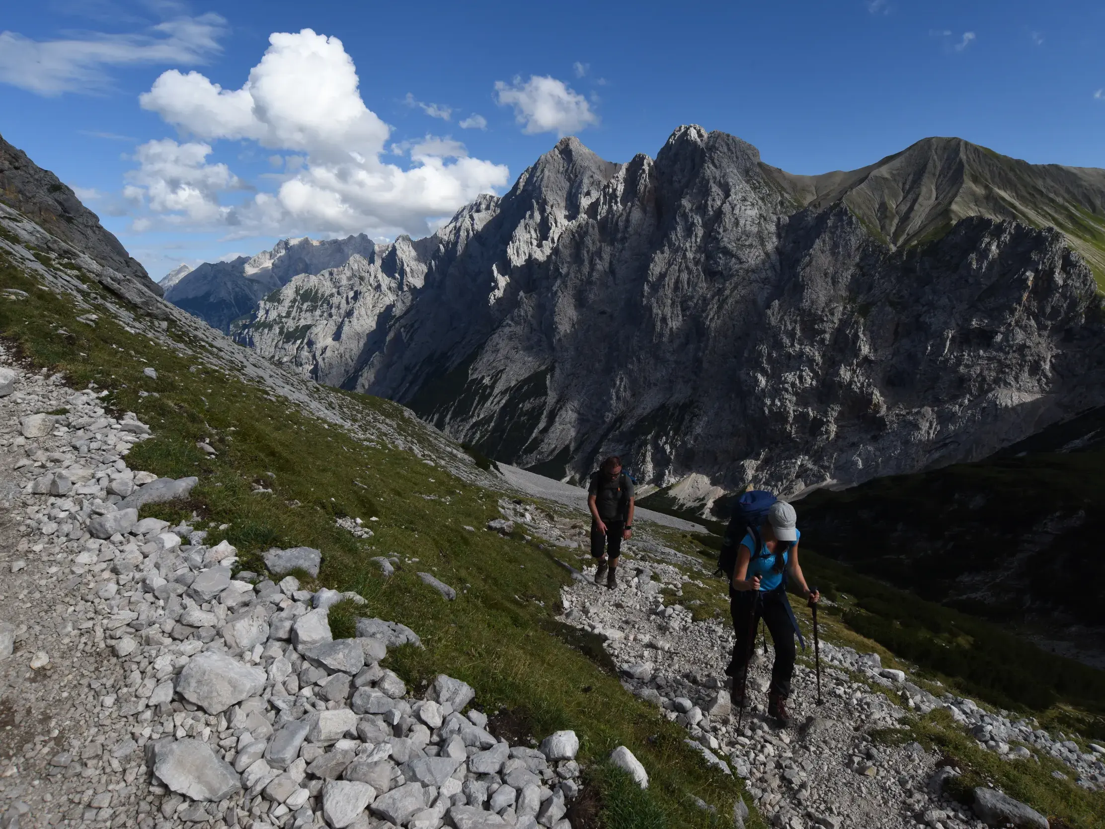 Zwei Wanderer mit Trekking-Ausrüstung auf einem steilen Geröllpfad im Reintal während einer Hüttenwanderung zur Zugspitze.