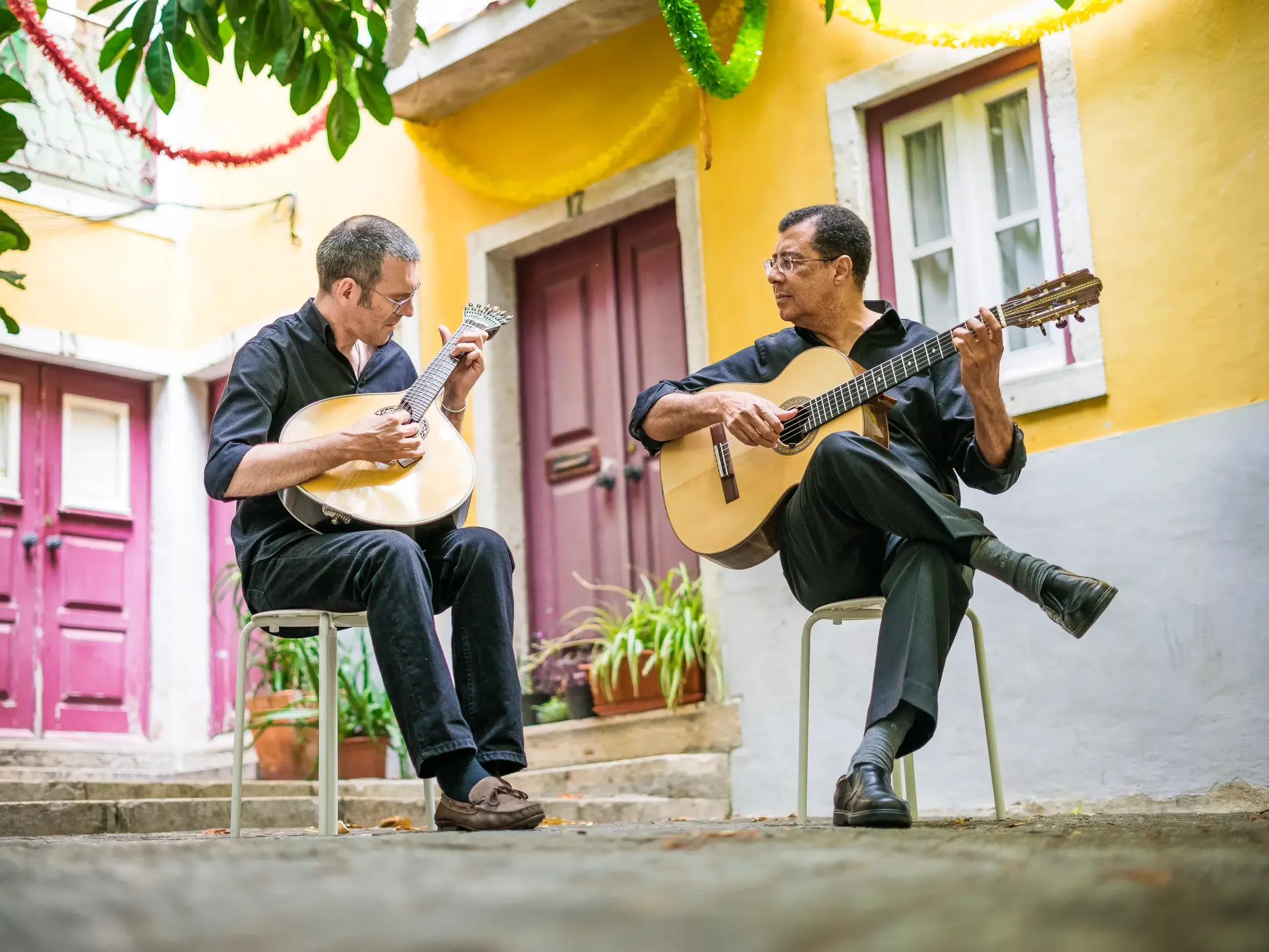 Zwei Musiker spielen traditionellen Fado in einem malerischen Innenhof in Coimbra auf einer klassischen und portugiesischen Gitarre.