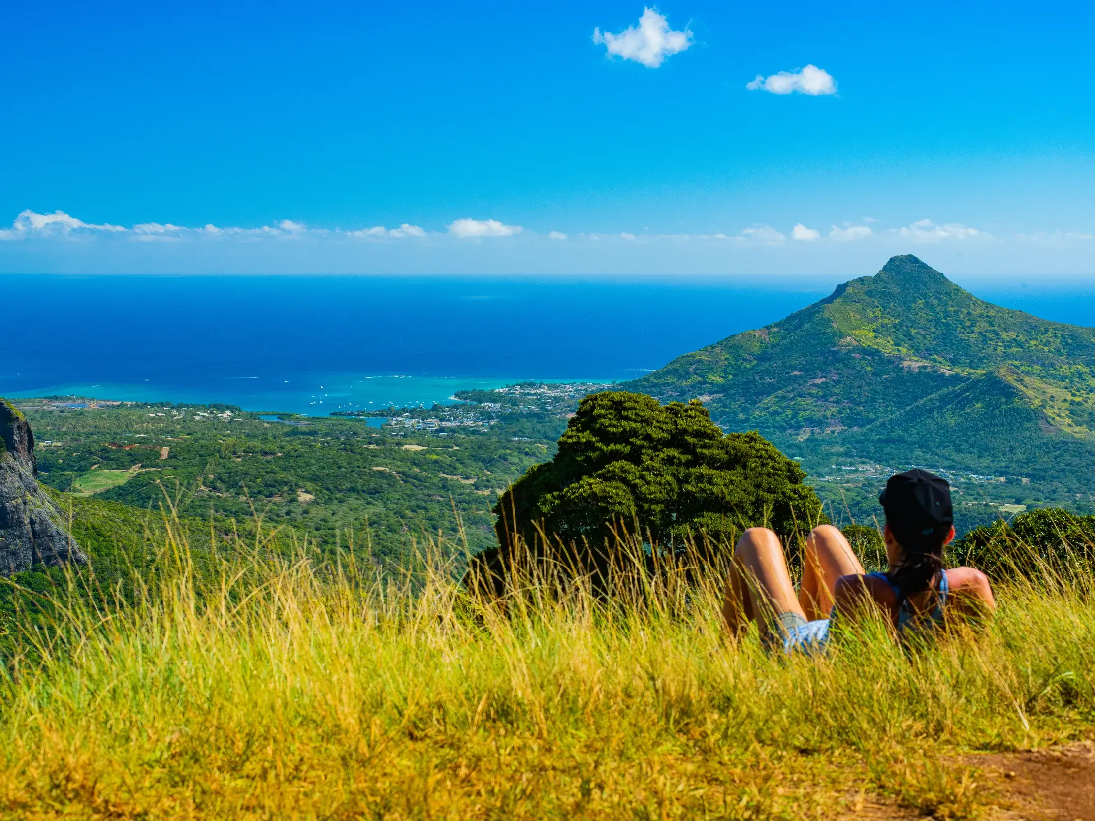 Wanderin bei einer Pause im Black-River-Gorges-Nationalpark mit Panoramablick auf die Küste von Mauritius.