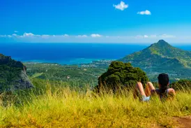 Wanderin bei einer Pause im Black-River-Gorges-Nationalpark mit Panoramablick auf die Küste von Mauritius.