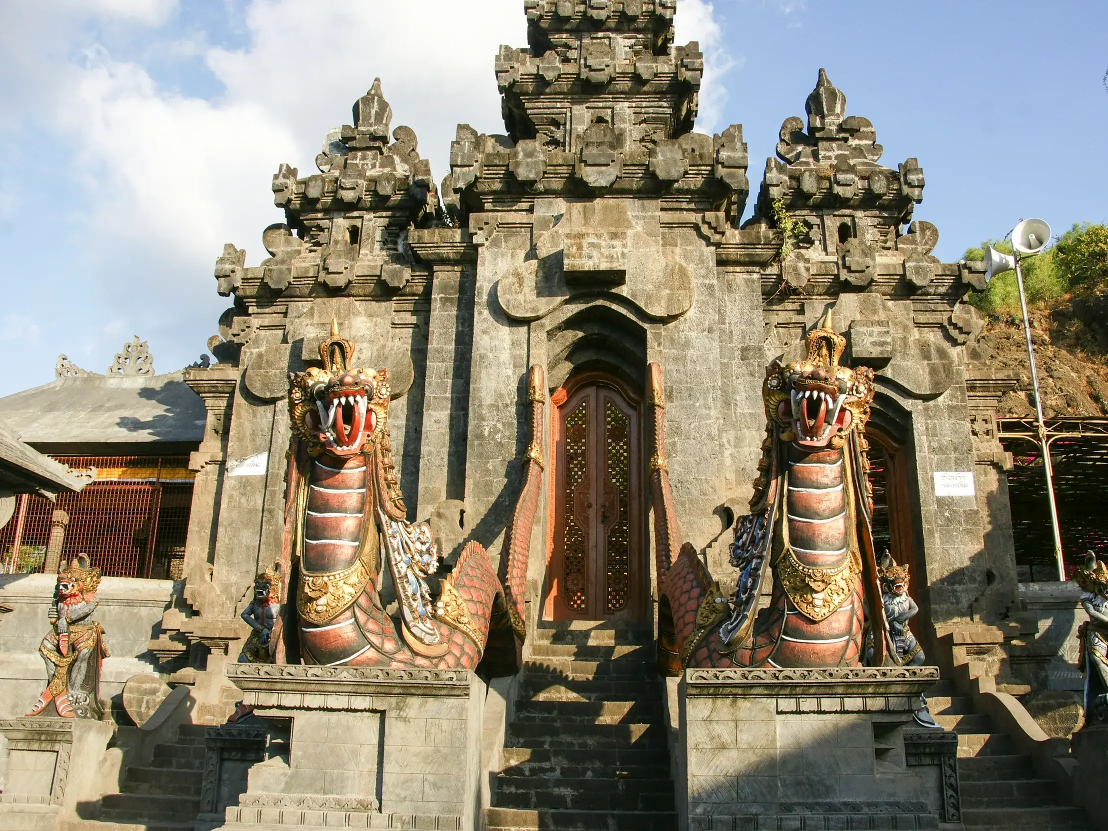 Steinerner Eingang des Hindu-Tempels Pura Pulaki auf Bali, bewacht von zwei großen, farbenprächtigen Naga-Drachenstatuen.
