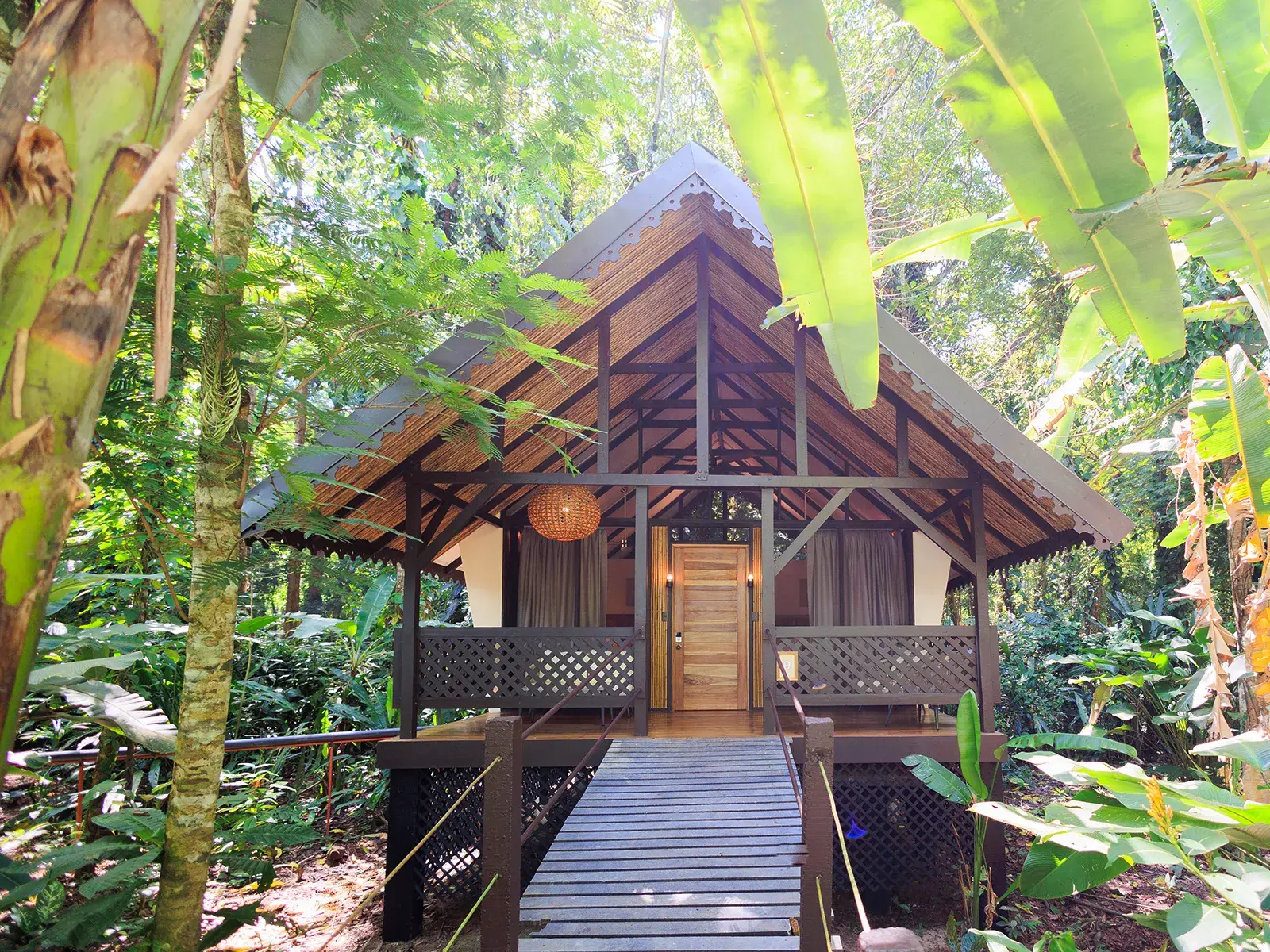 Einladender Holzbungalow des Hotels Almonds & Corals in Manzanillo, umgeben von der üppigen Vegetation des Regenwaldes in Costa Rica.