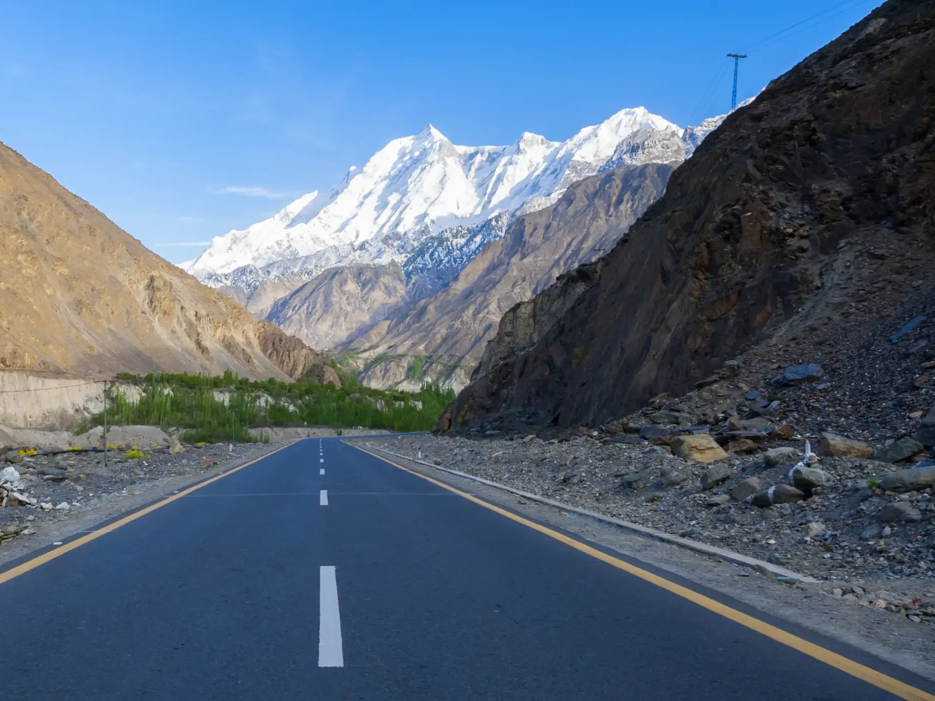 Der Karakorum Highway in Pakistan, gesäumt von kargen Felswänden, mit Blick auf den schneebedeckten Nanga Parbat.