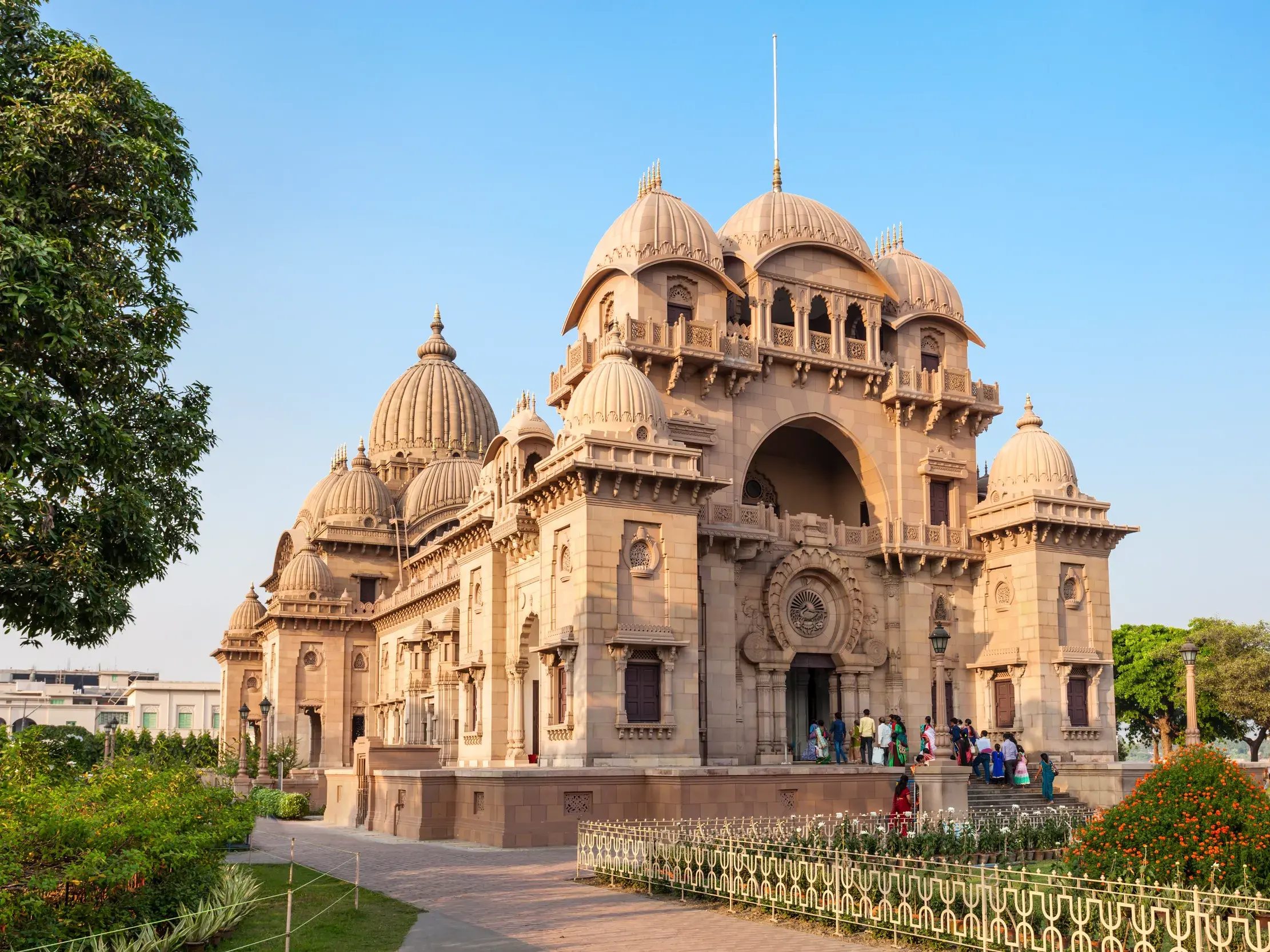 Der prachtvolle Belur Math Tempel in Kolkata mit seinen Gärten am Hugli-Fluss, umgeben von einem klaren blauen Himmel.