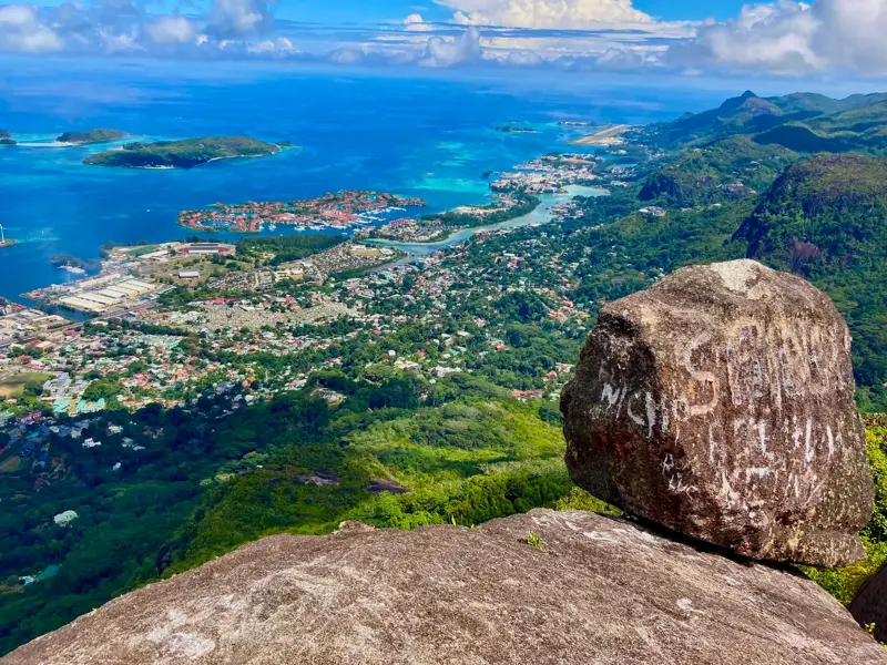 Panoramablick von einem Granitfelsen auf Mahé nach einer Wanderung mit Aussicht auf Victoria und das türkisfarbene Meer.