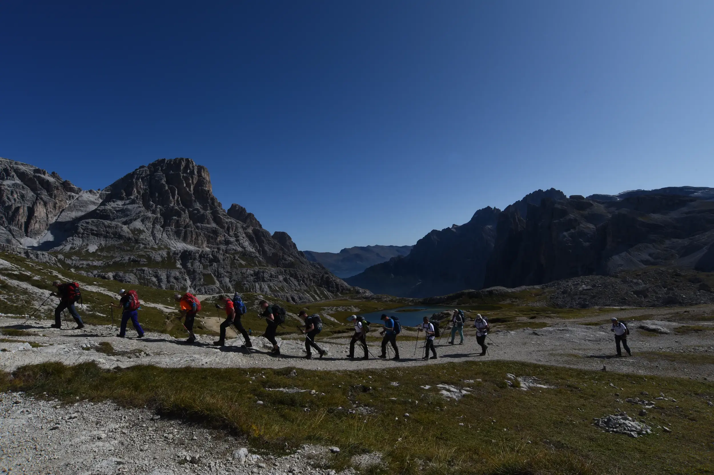 Eine Hauser-Wandergruppe beim Trekking auf einem Pfad vor der Felskulisse der Drei Zinnen im UNESCO Welterbe Dolomiten.