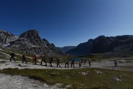 Eine Hauser-Wandergruppe beim Trekking auf einem Pfad vor der Felskulisse der Drei Zinnen im UNESCO Welterbe Dolomiten.