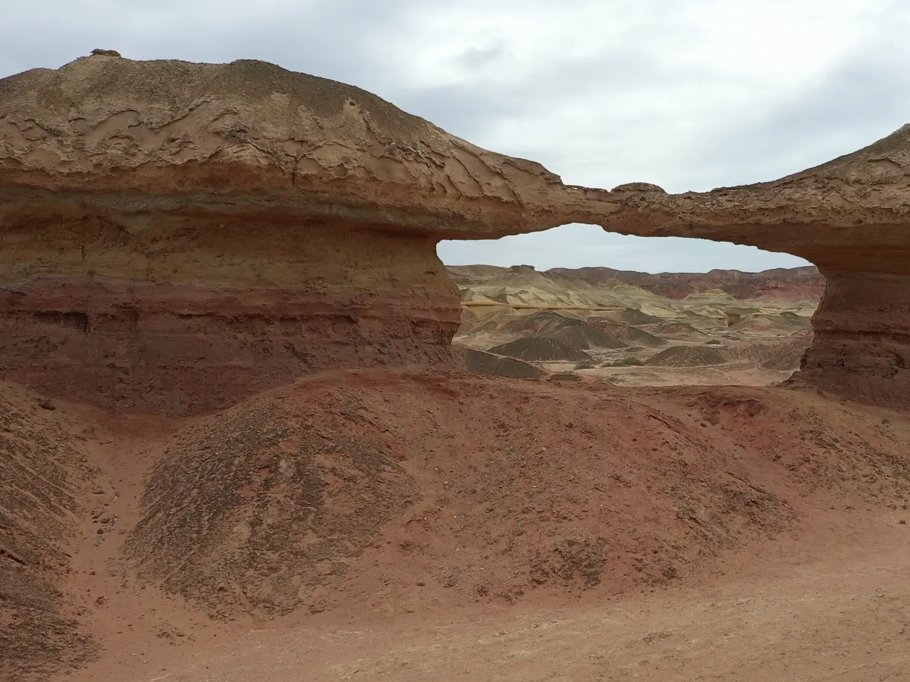 Imposanter, rötlicher Sandsteinbogen, geformt durch Erosion, im weiten Colinas Canyon in der Wüstenlandschaft Angolas.