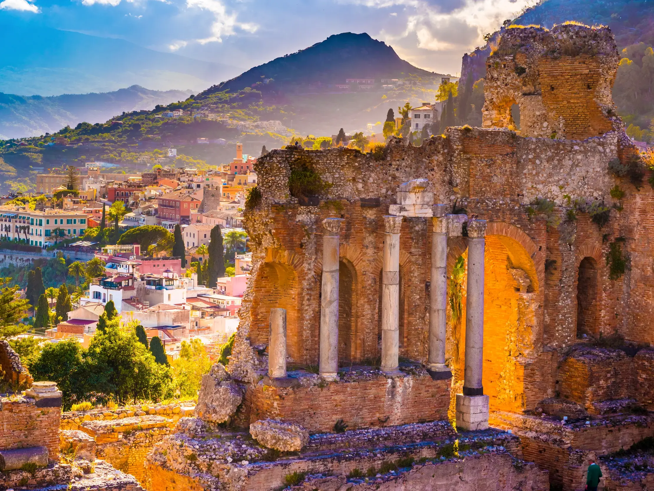 Die antiken Ruinen des Theaters von Taormina im warmen Abendlicht, mit malerischem Blick auf die Stadt und die Berge Siziliens.