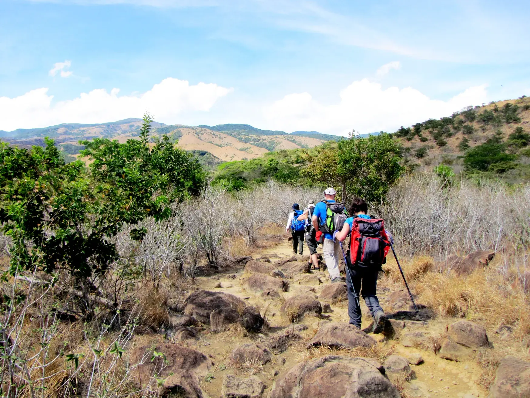 Eine Hauser-Reisegruppe wandert mit Rucksäcken auf einem steinigen Pfad im Rincón de la Vieja-Nationalpark.