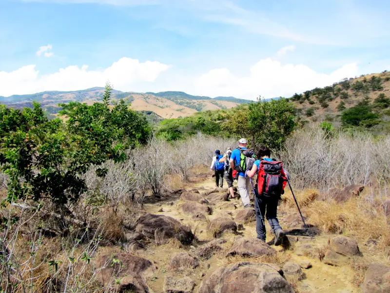 Eine Hauser-Reisegruppe wandert mit Rucksäcken auf einem steinigen Pfad im Rincón de la Vieja-Nationalpark.