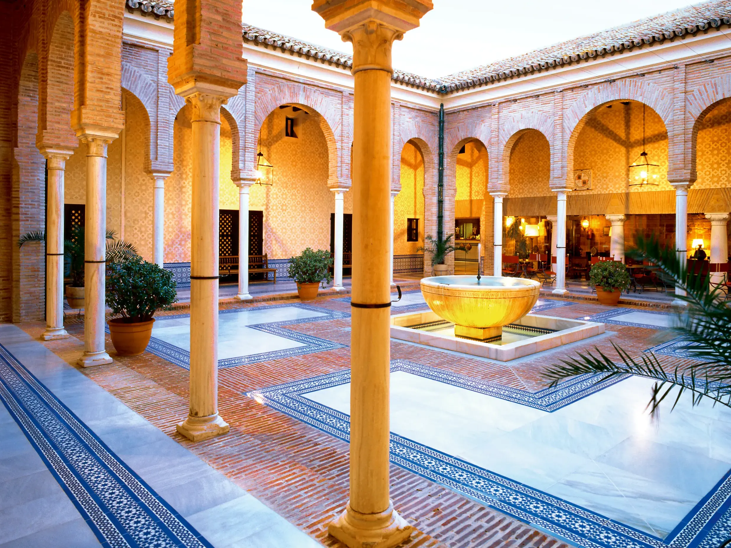 Eleganter Patio im Parador de Carmona in Andalusien mit Mudejar-Architektur, einem Säulengang und Zierbrunnen.
