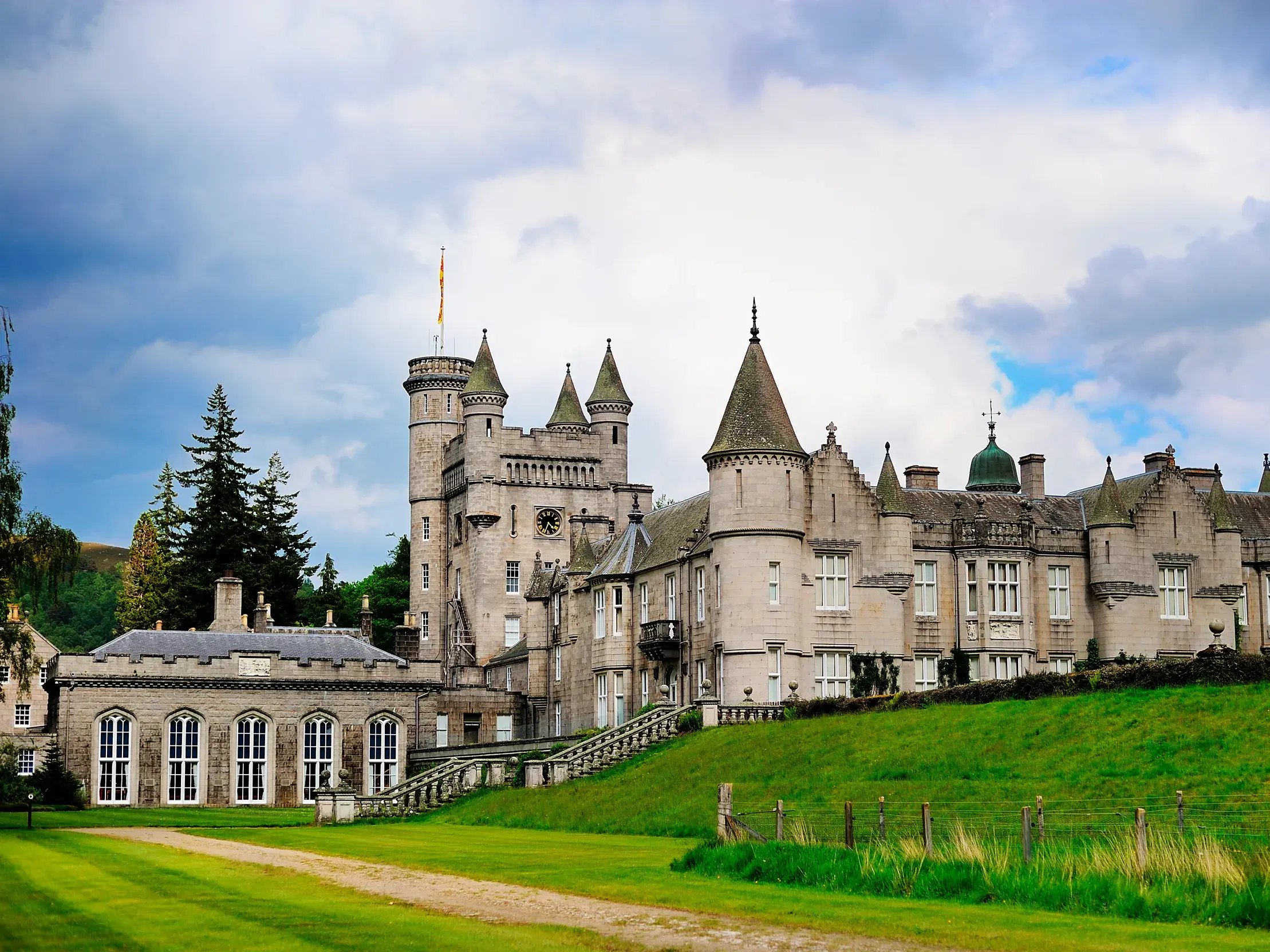 Das königliche Balmoral Castle mit seinen charakteristischen Türmen auf einem grünen Hügel in den schottischen Highlands.
