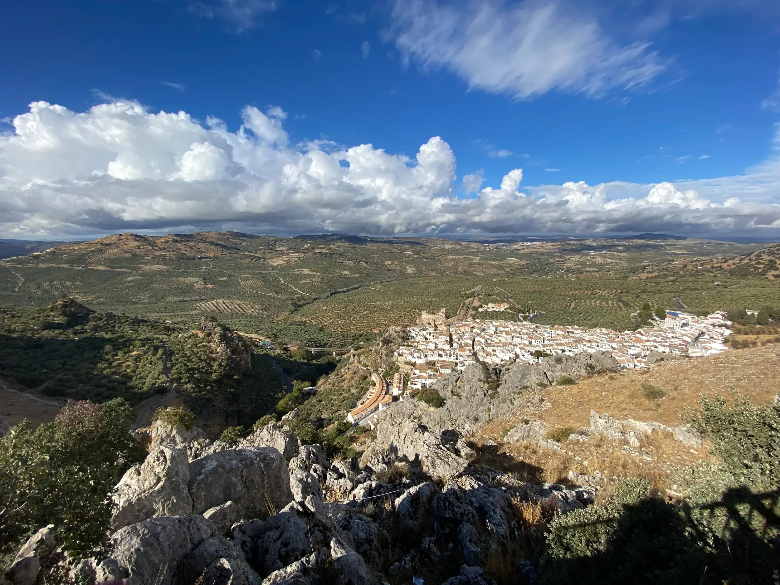 Wanderung in Andalusien: Blick von einem Berg auf das weiße Dorf Zuheros, eingebettet in die Hügel der Sierras Subbéticas.