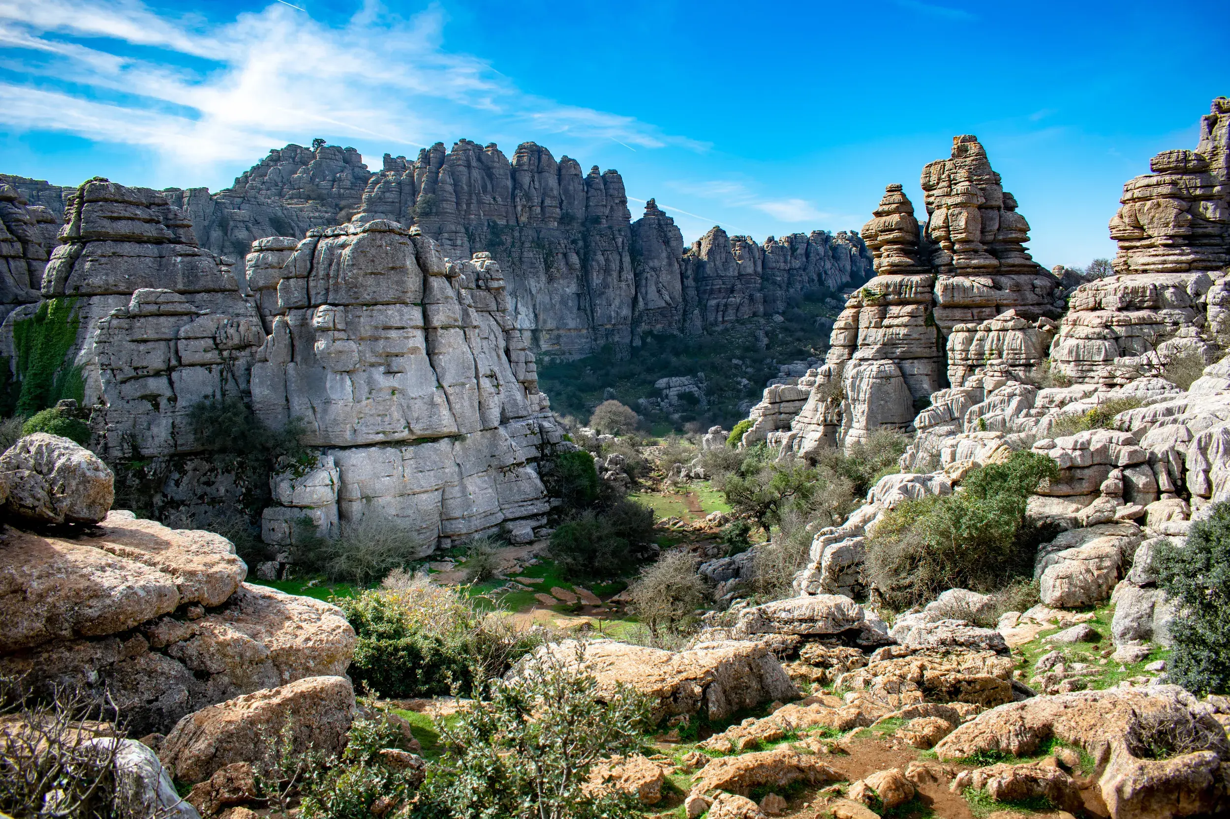 Ein Wanderpfad führt durch die bizarre Karstlandschaft aus Kalkstein im Naturpark El Torcal unter strahlend blauem Himmel.