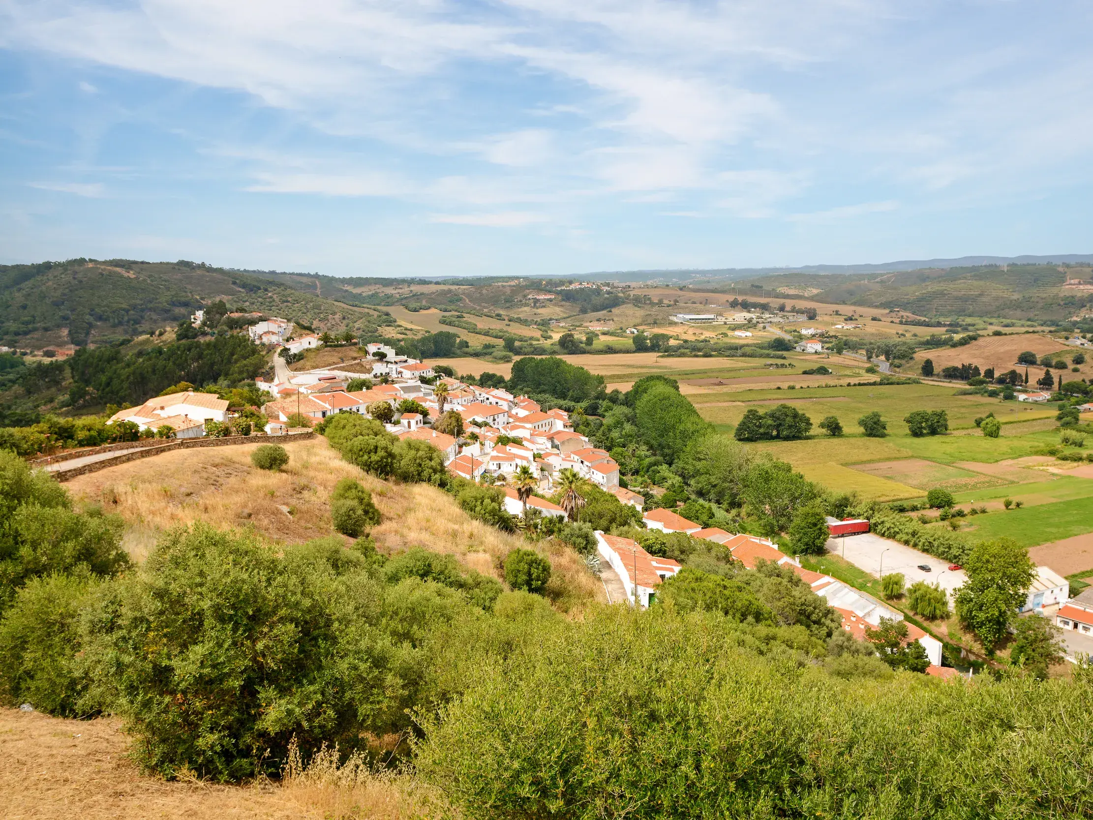 Weitblick über die grünen Hügel des Alentejo auf ein typisch portugiesisches Dorf mit weißen Häusern bei einer Wanderreise.