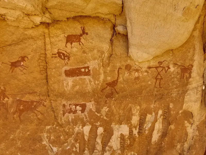 Uralte Felsbilder im Tassili n'Ajjer zeigen Jäger, Rinder und Antilopen an einer Felswand in der algerischen Sahara.