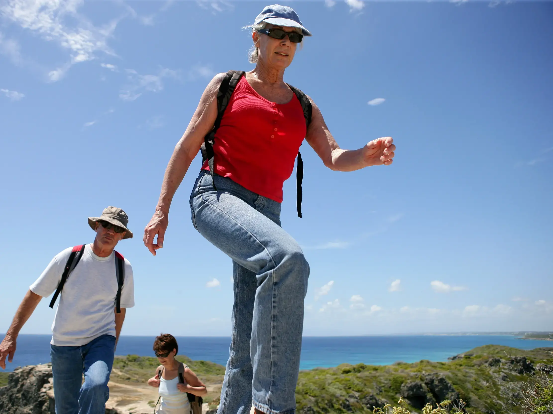 Eine kleine Wandergruppe erkundet bei einer Wanderreise auf Kreta einen felsigen Küstenpfad über dem blauen Mittelmeer.