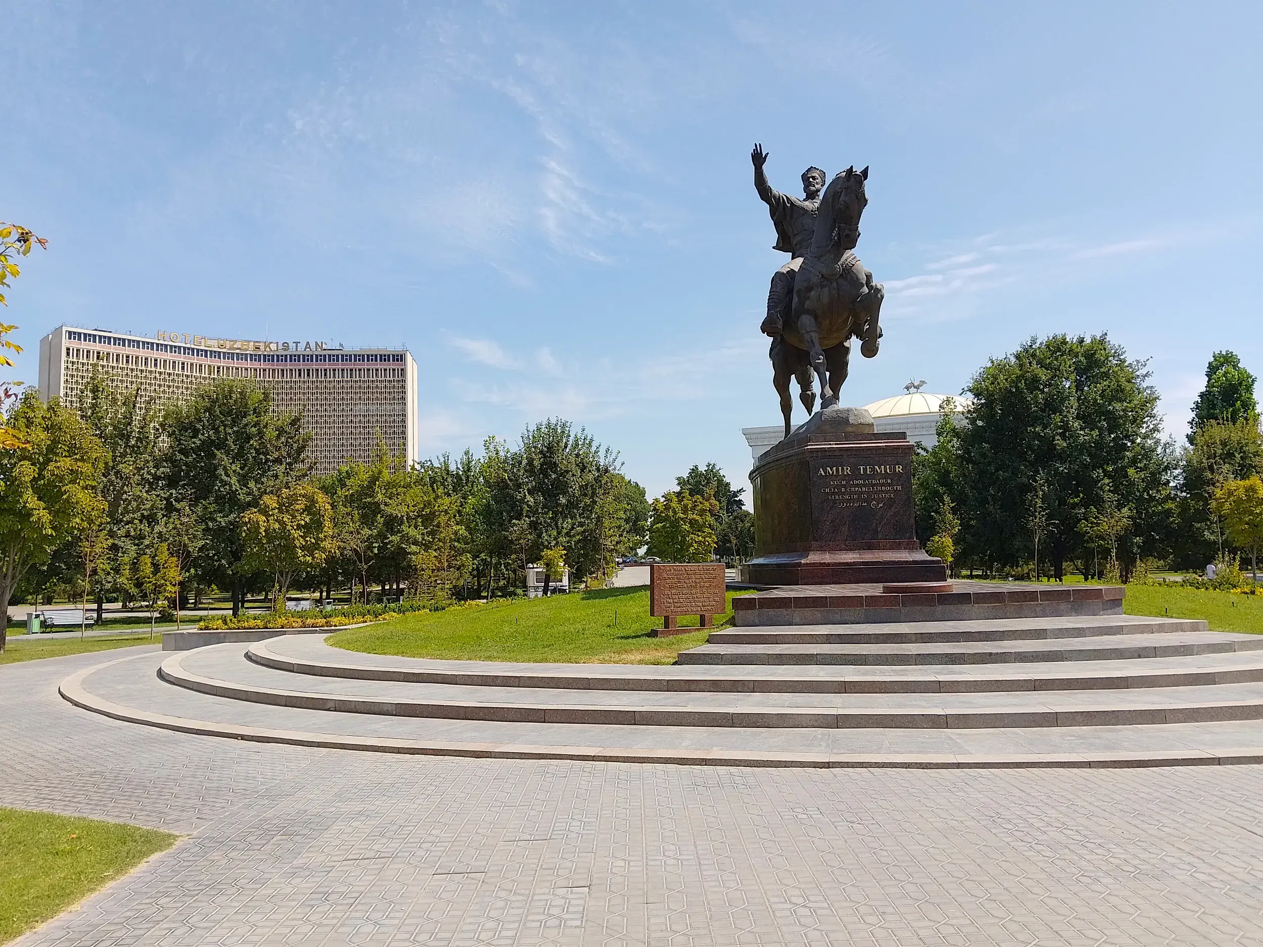 Bronzenes Reiterstandbild von Amir Timur in einem Park in Taschkent, der Hauptstadt Usbekistans, mit dem Hotel Usbekistan im Hintergrund.