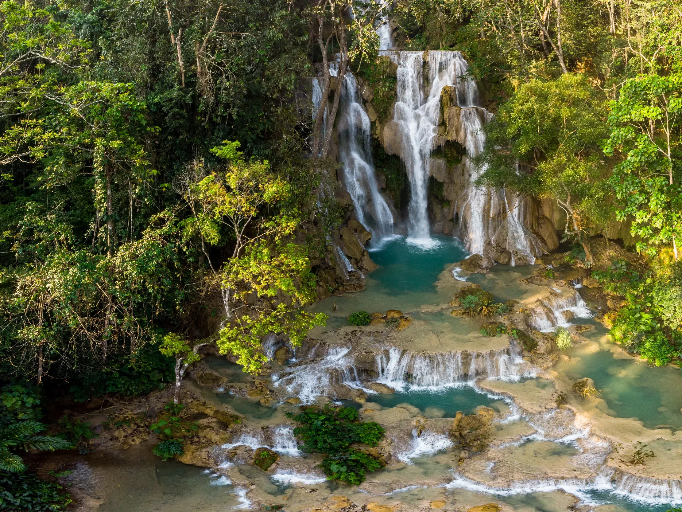 Die berühmten Kuang Sy Wasserfälle bei Luang Prabang stürzen über Kalksteinterrassen in türkise Becken im laotischen Dschungel.