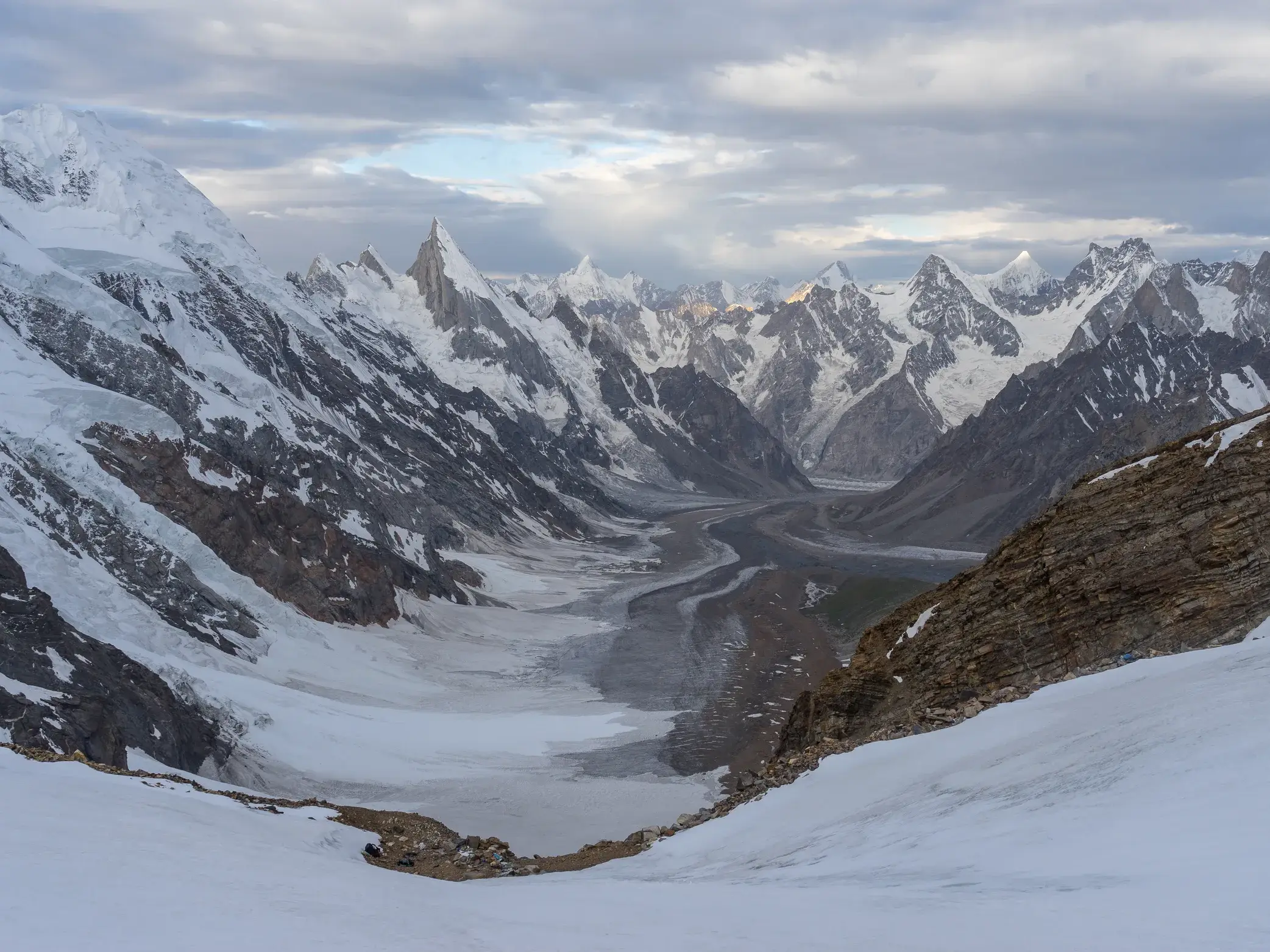 Panoramablick vom schneebedeckten Gondogoro-Pass auf den Gletscher und die spitzen Gipfel des Karakorum-Gebirges in Pakistan.