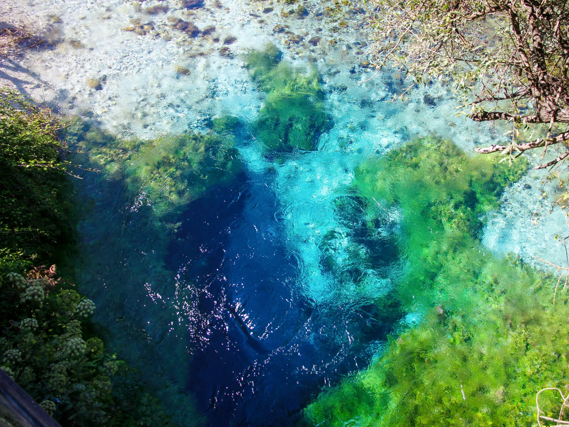 Vogelperspektive auf die Karstquelle Syri i Kalter in Albanien, deren Wasser in magischen Blau- und Grüntönen schimmert.