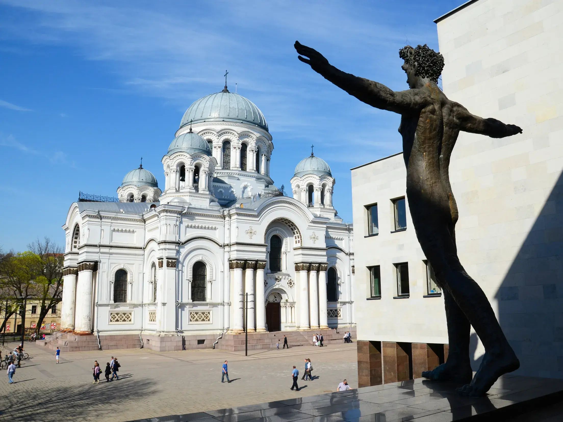 Bronzestatue mit ausgestreckten Armen vor der strahlend weißen, neobyzantinischen Soboras-Kirche in Kaunas, Litauen.