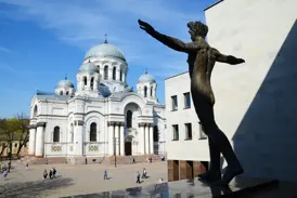 Bronzestatue mit ausgestreckten Armen vor der strahlend weißen, neobyzantinischen Soboras-Kirche in Kaunas, Litauen.