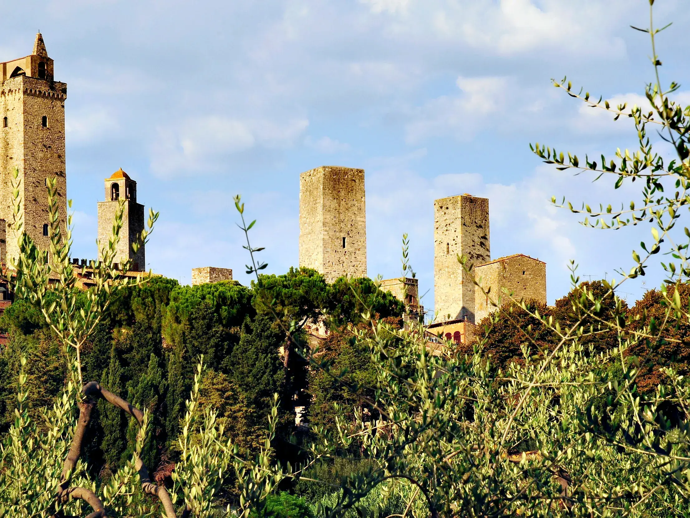 Die berühmten Geschlechtertürme von San Gimignano ragen bei einer Wanderung auf der Via Francigena aus der Toskana-Hügellandschaft.