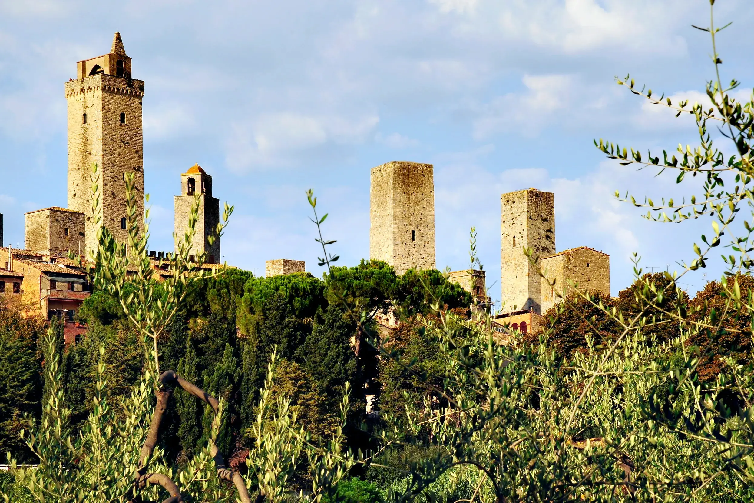 Die berühmten Geschlechtertürme von San Gimignano ragen bei einer Wanderung auf der Via Francigena aus der Toskana-Hügellandschaft.