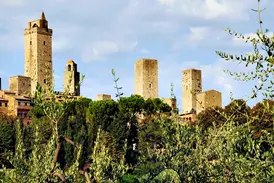Die berühmten Geschlechtertürme von San Gimignano ragen bei einer Wanderung auf der Via Francigena aus der Toskana-Hügellandschaft.