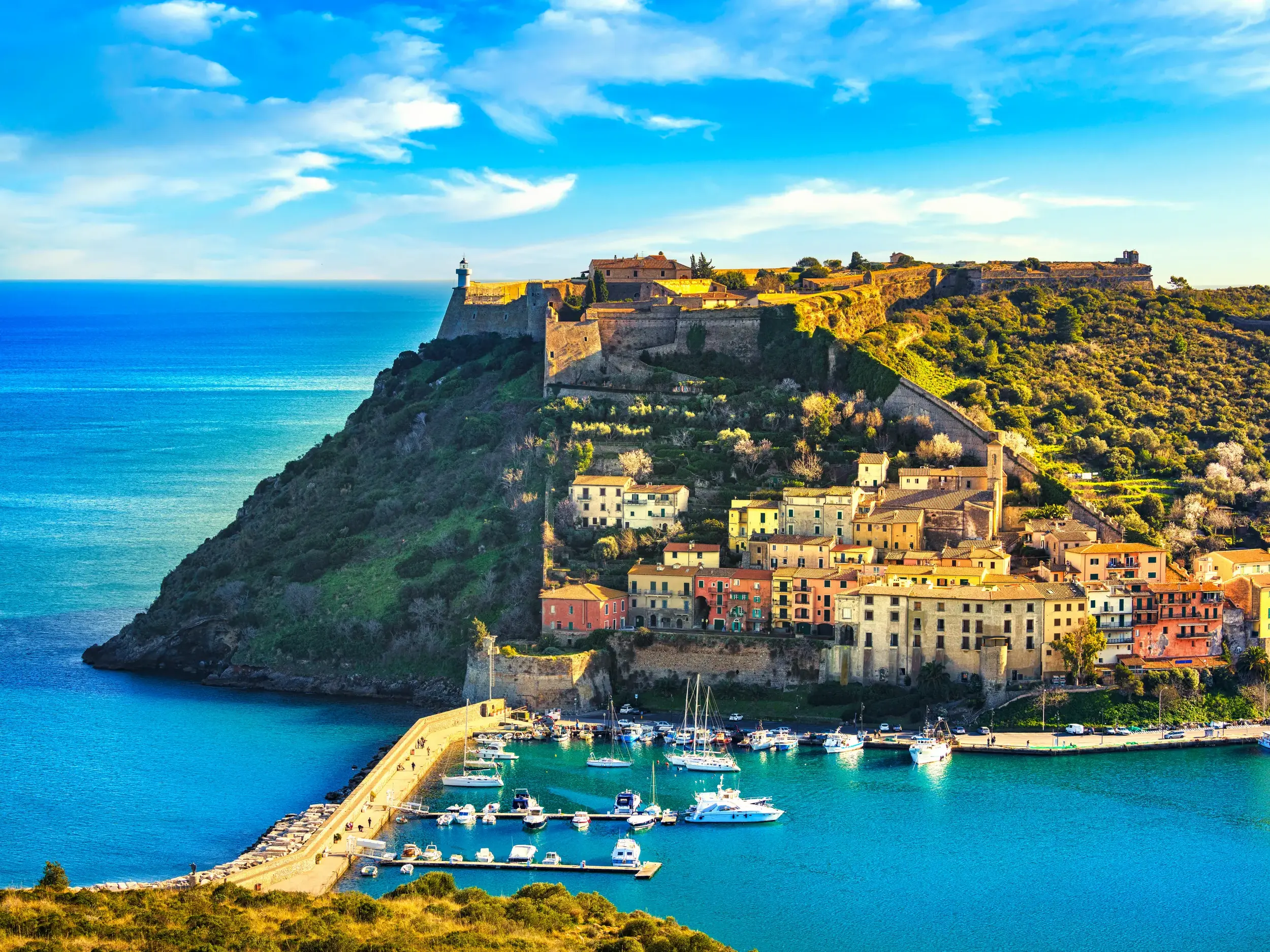 Idyllische Bucht und Hafen von Porto Ercole auf Monte Argentario mit bunten Häusern und historischer Festungsanlage.