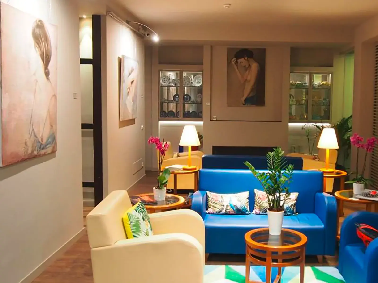 Künstlerisch gestalteter Loungebereich im Hotel Lucerna in Castiglione della Pescaia mit modernen Möbeln und Gemälden.