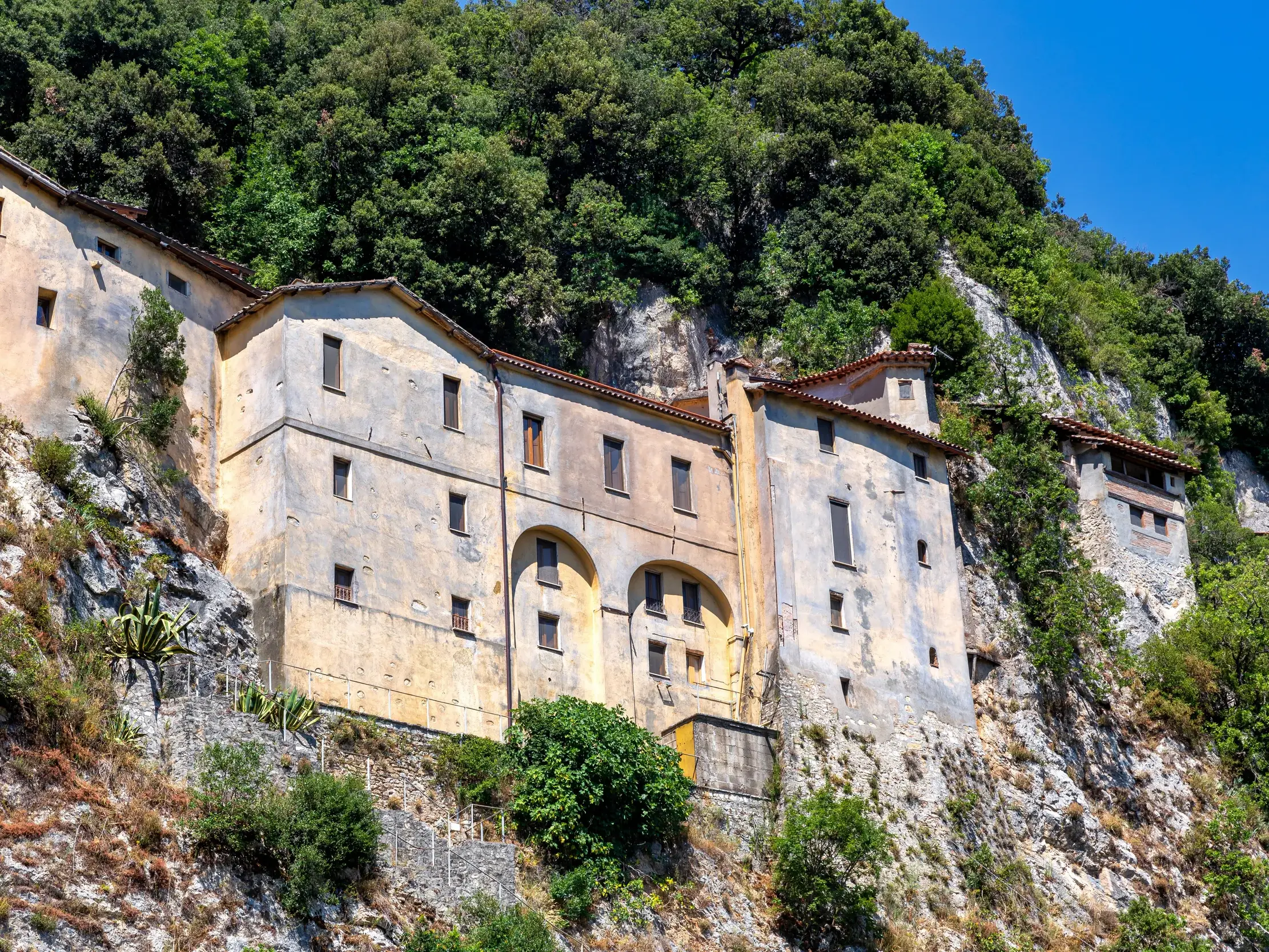 Das historische Kloster von Greccio, erbaut an einer steilen Felswand, umgeben von dichten Wäldern im Heiligen Tal von Rieti.
