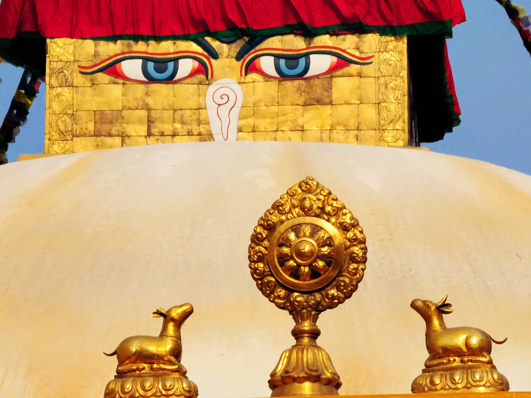 Goldenes Dharma-Rad mit zwei Hirschen und die Augen Buddhas auf der weißen Kuppel des Bodnath-Stupa in Kathmandu.
