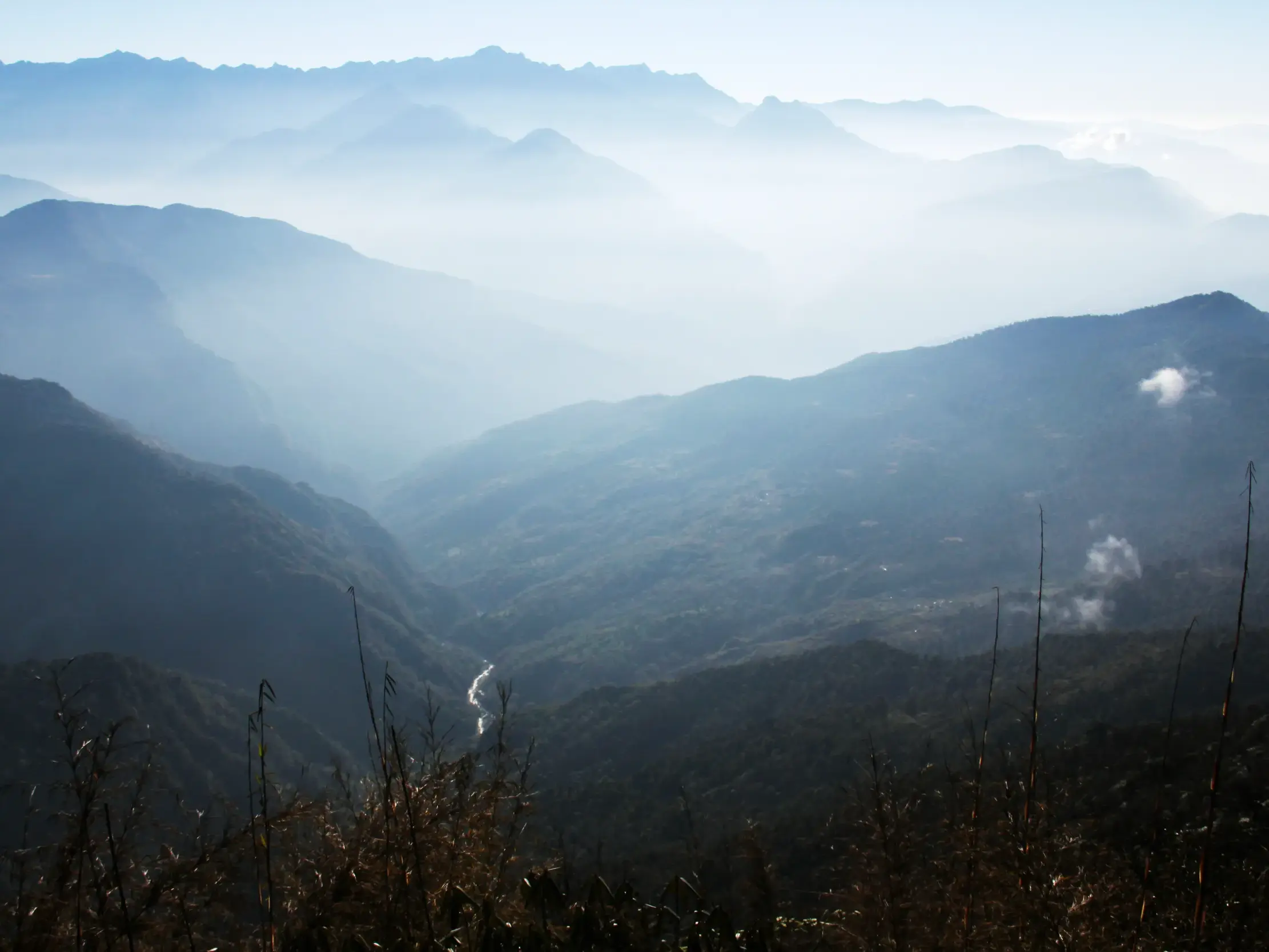 Majestätische Aussicht beim Trekking in Nepal: gestaffelte Bergketten im Morgennebel über dem tiefen Arun-Flusstal.