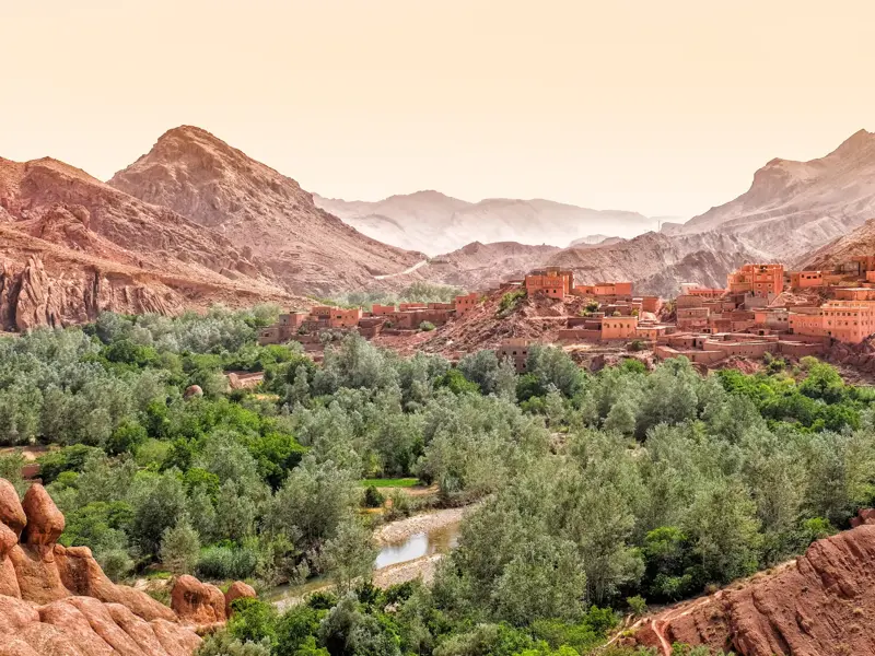 Traditionelle Kasbahs aus Lehm thronen über einer grünen Oase im Dadès-Tal während einer Hauser Trekkingreise in Marokko.