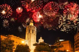 Rotes und goldenes Silvester-Feuerwerk explodiert am Nachthimmel über dem Glockenturm der Kathedrale in der Altstadt von Valencia.