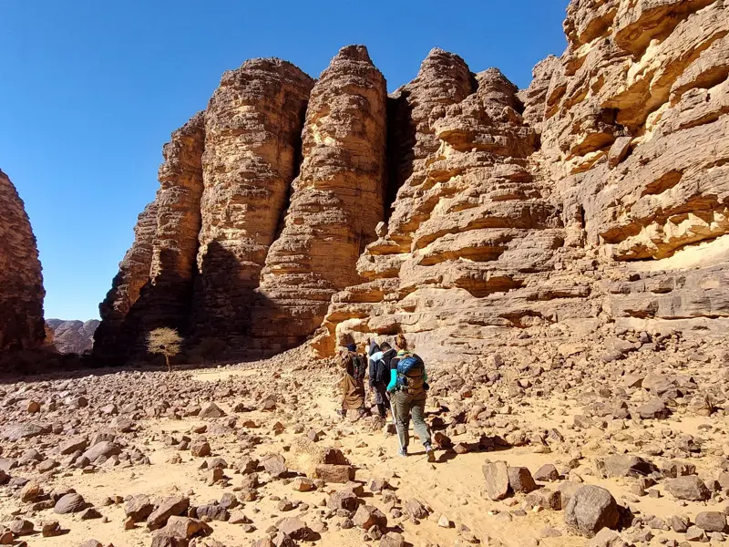 Hauser Reisegruppe auf einer Trekking-Tour durch eine Schlucht mit hohen Sandsteinfelsen im Tassili n'Ajjer Nationalpark.