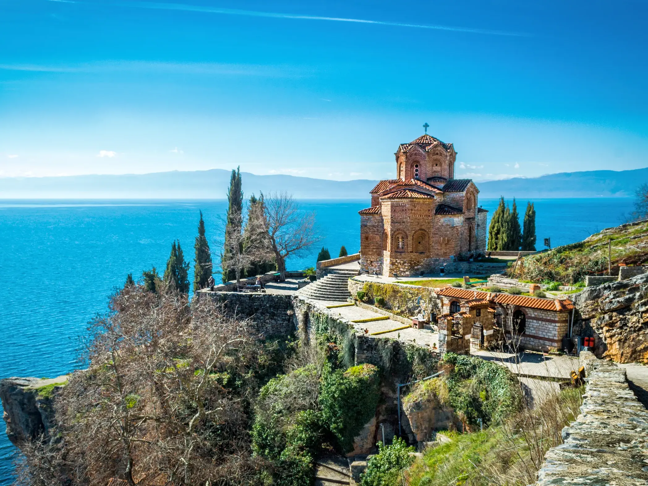 Die Kaneokirche in Ohrid thront auf einer Klippe über dem tiefblauen Wasser des Ohrid-Sees an einem sonnigen Tag.