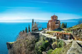 Die Kaneokirche in Ohrid thront auf einer Klippe über dem tiefblauen Wasser des Ohrid-Sees an einem sonnigen Tag.