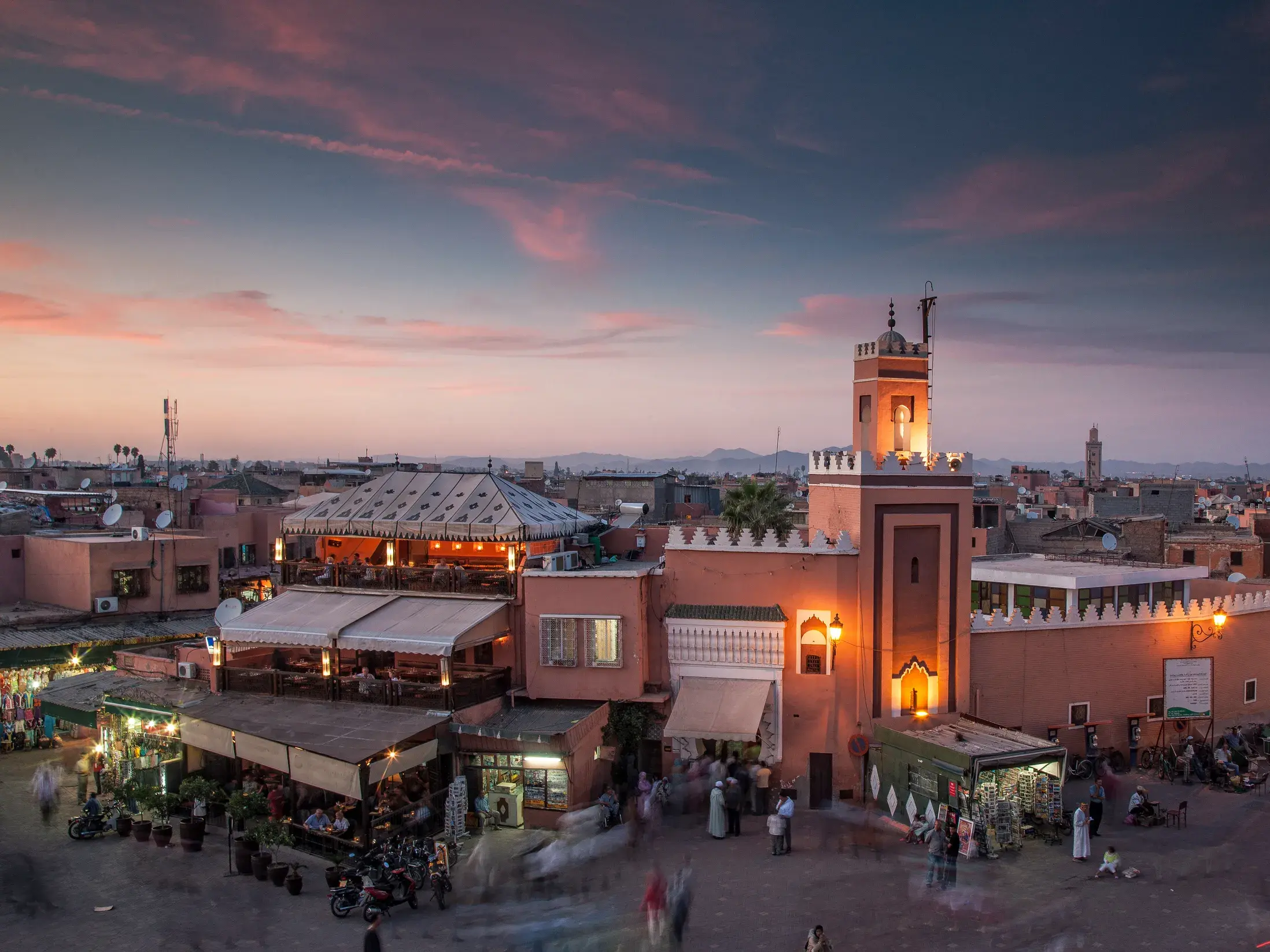 Genießen Sie auf Ihrer Studienreise von einer Dachterrasse den abendlichen Blick über die Dächer der Medina von Marrakesch auf den belebten Platz Djemaa el-Fna.