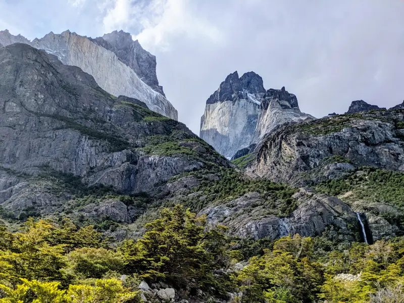 Blick vom W-Trek auf steile Felswände und grüne Wälder im Französischen Tal des Torres del Paine Nationalparks in Patagonien.