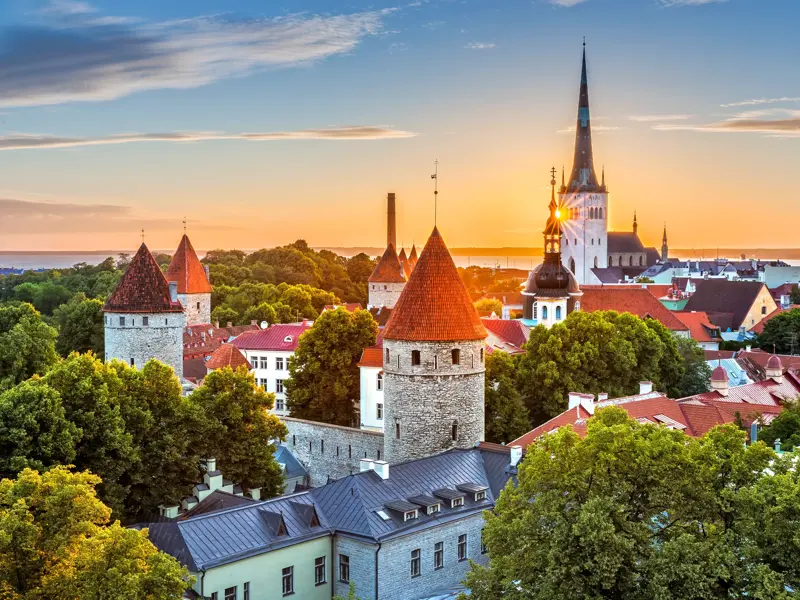 Blick vom Domberg auf die mittelalterlichen Türme und die Olaikirche in der Altstadt von Tallinn bei Sonnenuntergang.