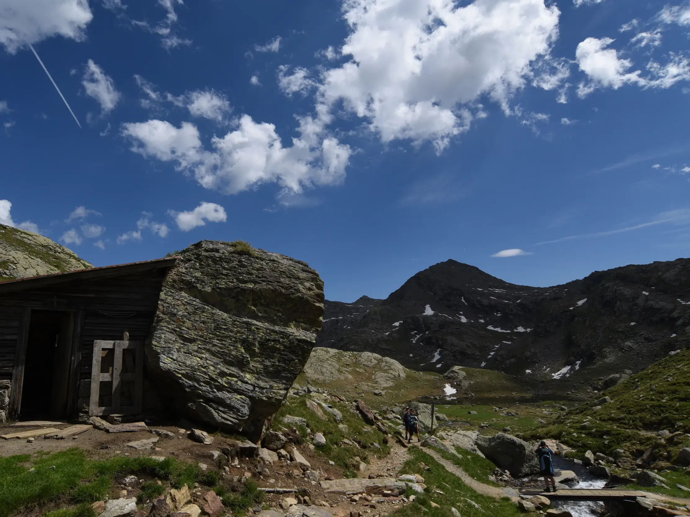 Urige Almhütte auf dem Weg zur Bockerhütte nahe den Spronser Seen, mit Wanderern im alpinen Gelände der Texelgruppe.